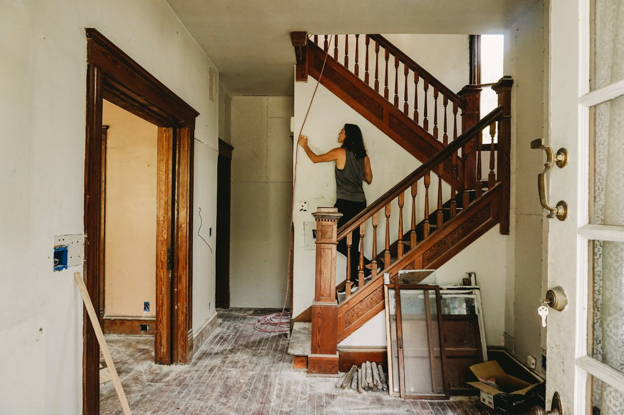 about-me A woman working on home renovation featuring a wooden staircase.
