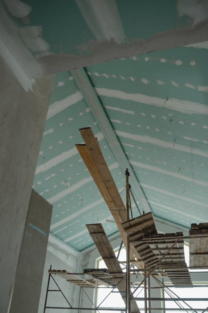Mastering the First Impression: Your intriguing post title goes here Scaffolding setup in an interior construction space with suspended ceiling boards and wooden planks.